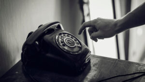 A hand reaching for a rotary phone